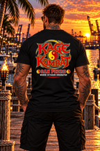 A man stands on a dock at sunset wearing a black T-shirt with a large 'Kage Kombat San Pedro' graphic on the back, with a tropical harbor and port cranes in the background.